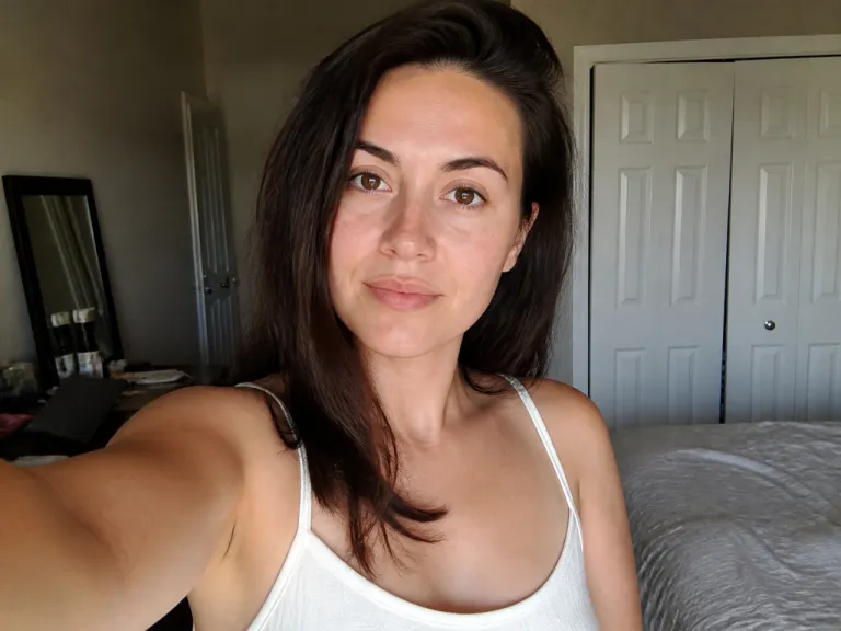 Before Online Smile Editing A Mobile Selfie Shows A Neutral Expression Against The Same Indoor Background